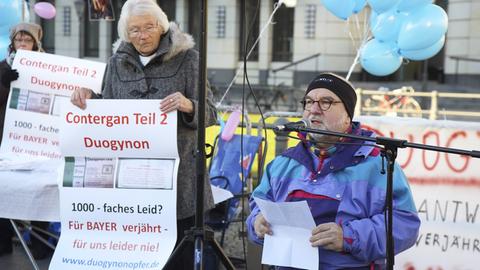 Drei Personen von der Interessengemeinschaft Duogynonopfer stehen im November 2016 vor dem Brandenburger Tor in Berlin und demonstrieren. Duogynon, ein hormoneller Schwangerschaftstest der Schering AG, wurde von 1950 bis 1981 verkauft und steht im Verdacht, tausende Missbildungen verursacht zu haben.