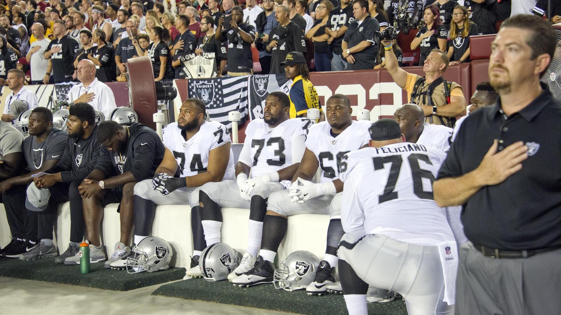 Spieler der Oakland Raiders bleiben bei der US-Hymne vor einem NFL-Spiel sitzen. Spieler der Oakland Raiders bleiben bei der US-Hymne vor einem NFL-Spiel sitzen.