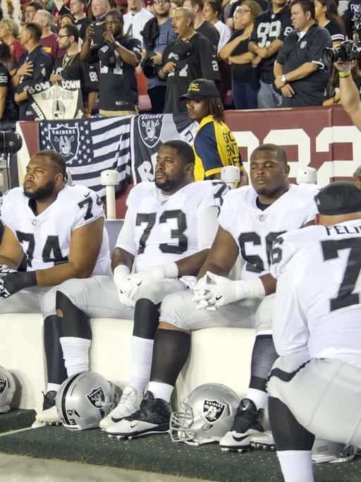 Spieler der Oakland Raiders bleiben bei der US-Hymne vor einem NFL-Spiel sitzen.