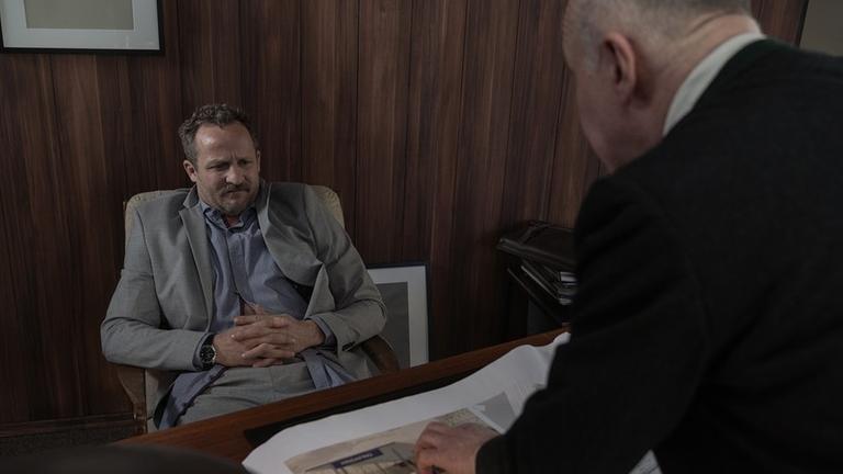 Der korrupte Politiker Zischl ist auf dem Bild hinter seinem Schreibtisch sitzend zu sehen, während er ein unmoralisches Angebot bekommt. Filmstill aus der Serie "Hindafing". Der korrupte Politiker Zischl ist auf dem Bild hinter seinem Schreibtisch sitzend zu sehen, während er ein unmoralisches Angebot bekommt. Filmstill aus der Serie "Hindafing".