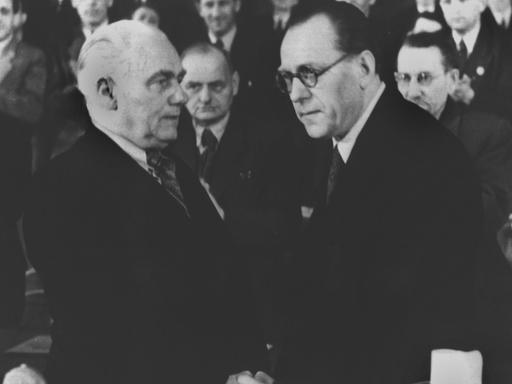 Symbolischer Händedruck zwischen Willhem Pieck, dem Vorsitzenden der KPD (l), und dem SPD-Vorsitzenden Otto Grotewohl (r) in der Berliner Staatsoper in der sowjetischen Besatzungszone im April 1946. Die beiden Parteien verschmolzen zur Sozialistischen Einheitspartei Deutschlands (SED).