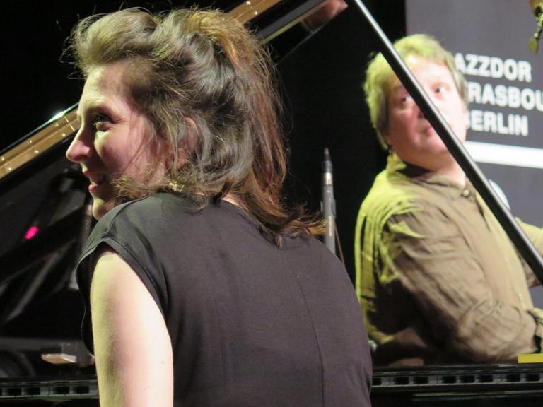 Eve Risser sitzt hinter einem Flügel und schaut lachend zur Seite, der Kontrabassist Benjamin Duboc spielt im Hintergrund. Jazzdor Festival 2019 in Berlin