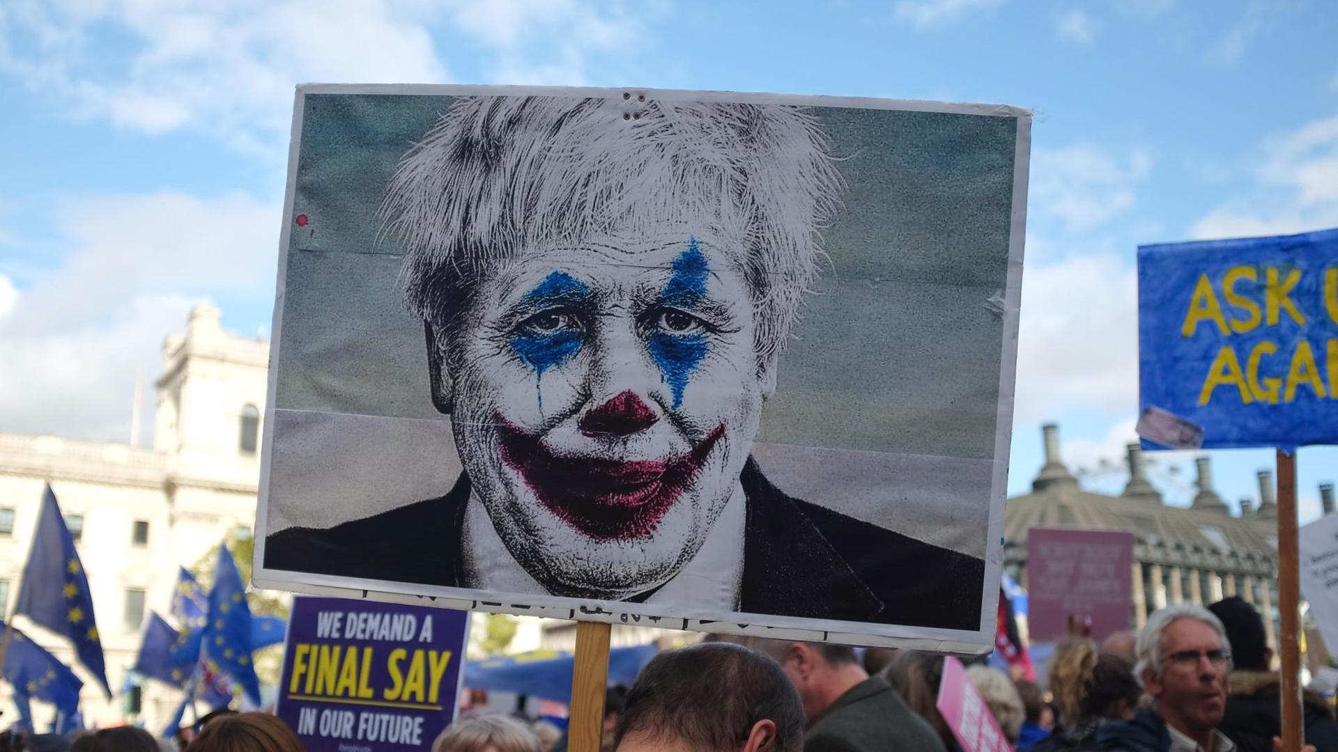 person holding sign with picture of a man wearing clown face art person holding sign with picture of a man wearing clown face art