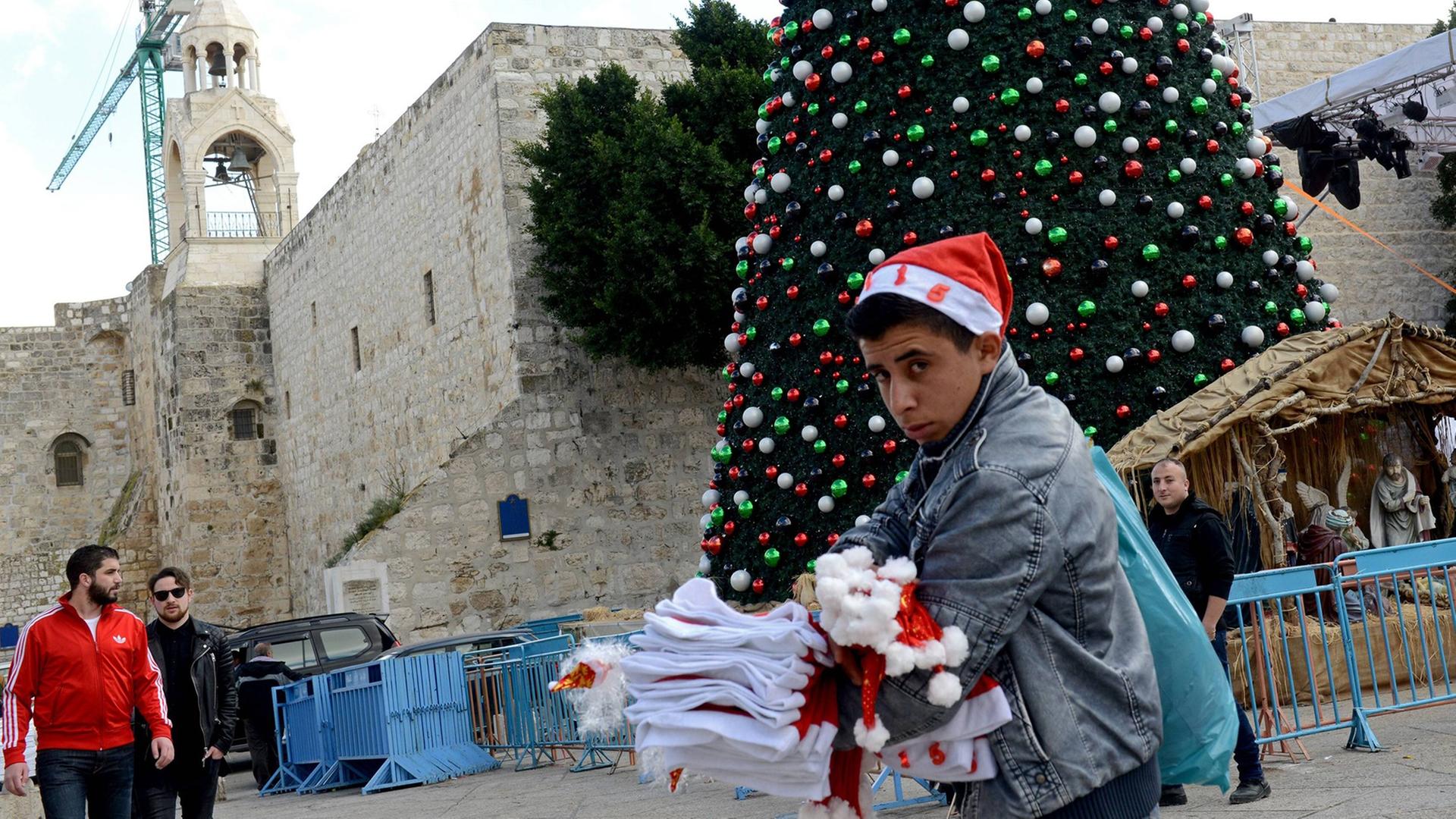 Ein palästinensischer Junge verkauft Weihnachtsmützen auf dem Manger Platz vor der Geburtskirche Jesu in Bethlehem. Ein palästinensischer Junge verkauft Weihnachtsmützen auf dem Manger Platz vor der Geburtskirche Jesu in Bethlehem.