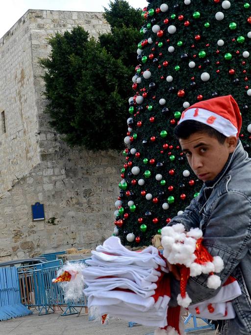 Ein palästinensischer Junge verkauft Weihnachtsmützen auf dem Manger Platz vor der Geburtskirche Jesu in Bethlehem.