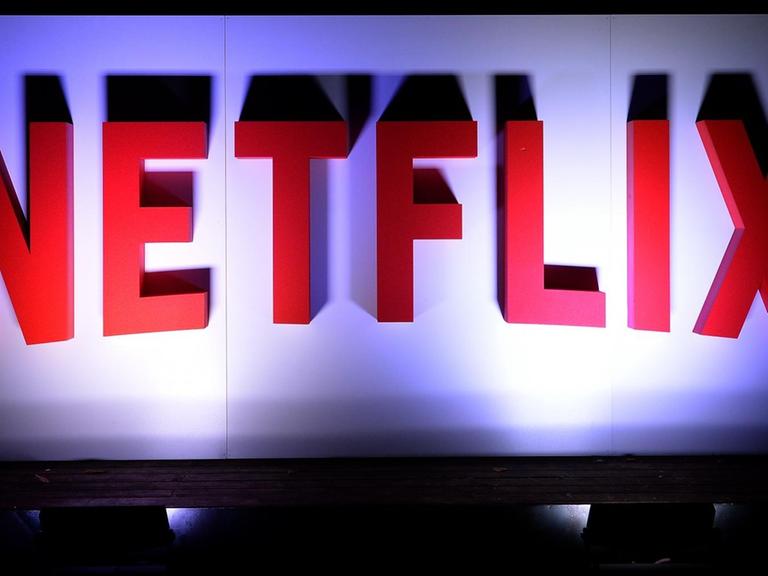Das Firmenlogo des Streaminganbieters Netflix in großen, roten, dreidimensionalen Buchstaben an einer weißen Wand, von unten angestrahlt.