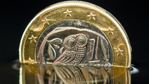 Eine griechische Euro-Münze spiegelt sich in einer Wasserfläche.