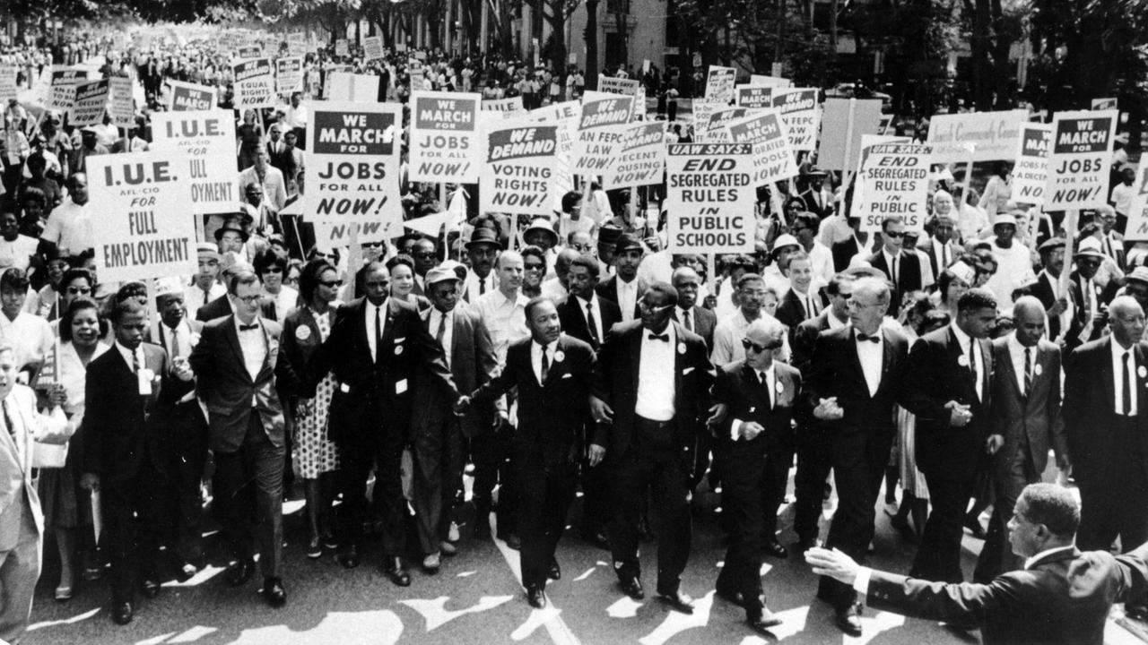 Beim "March on Washington for Jobs and Freedom" (1963) ist eine große Menschenmenge zu sehen, die Schilder mit ihren Forderungen halten. In der ersten Reihe Martin Luther King Jr. (vorne, 7.v.re.). Beim "March on Washington for Jobs and Freedom" (1963) ist eine große Menschenmenge zu sehen, die Schilder mit ihren Forderungen halten. In der ersten Reihe Martin Luther King Jr. (vorne, 7.v.re.).