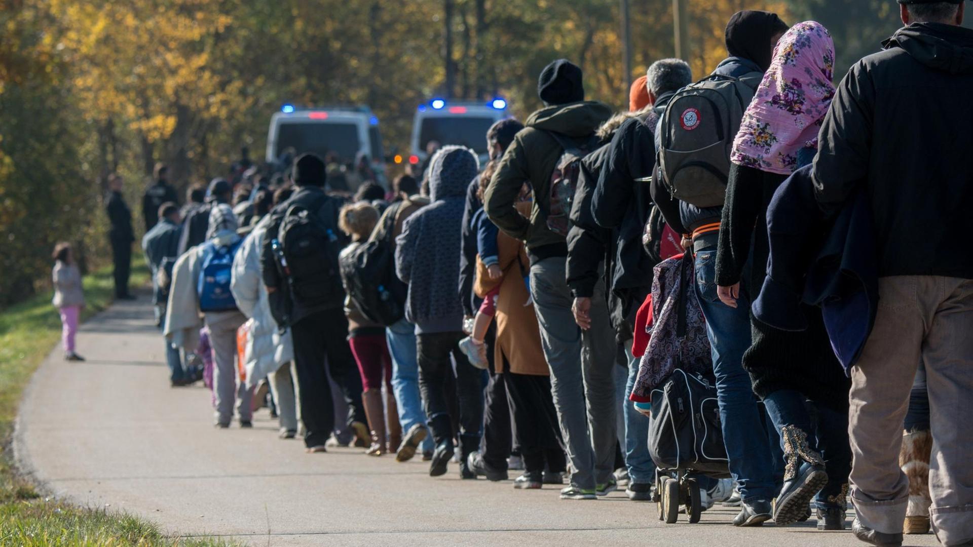 Flüchtlinge gehen nahe Wegscheid hinter Fahrzeugen der Bundespolizei Flüchtlinge gehen nahe Wegscheid hinter Fahrzeugen der Bundespolizei