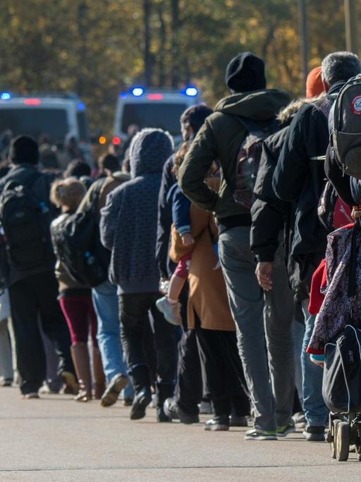 Flüchtlinge gehen nahe Wegscheid hinter Fahrzeugen der Bundespolizei