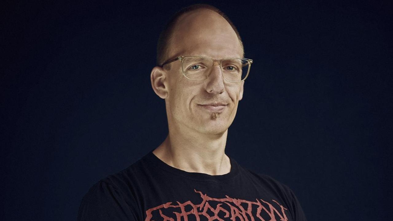 Jörg Scheller trägt eine Brille und ein schwarzes T-Shirt mit dem Namensschriftzug einer Heavy Metal Band Jörg Scheller trägt eine Brille und ein schwarzes T-Shirt mit dem Namensschriftzug einer Heavy Metal Band