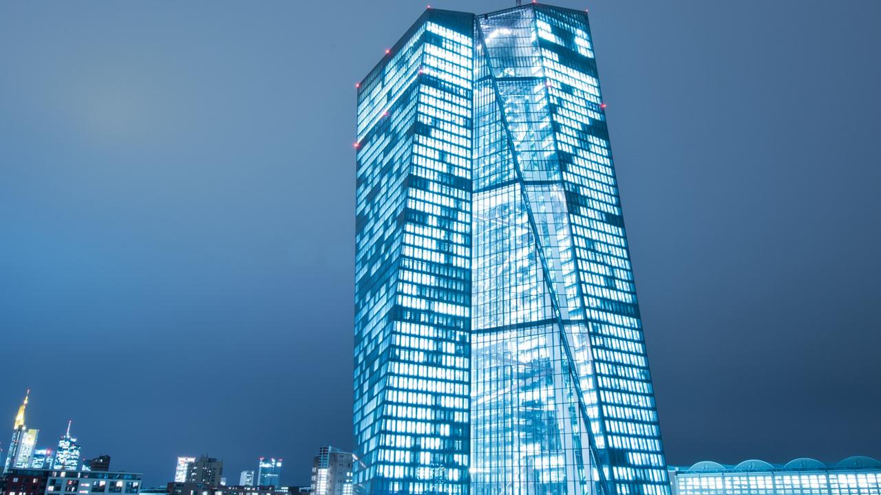 Das EZB-Gebäude mit erleuchteten Fenstern vor dem Abendhimmel.