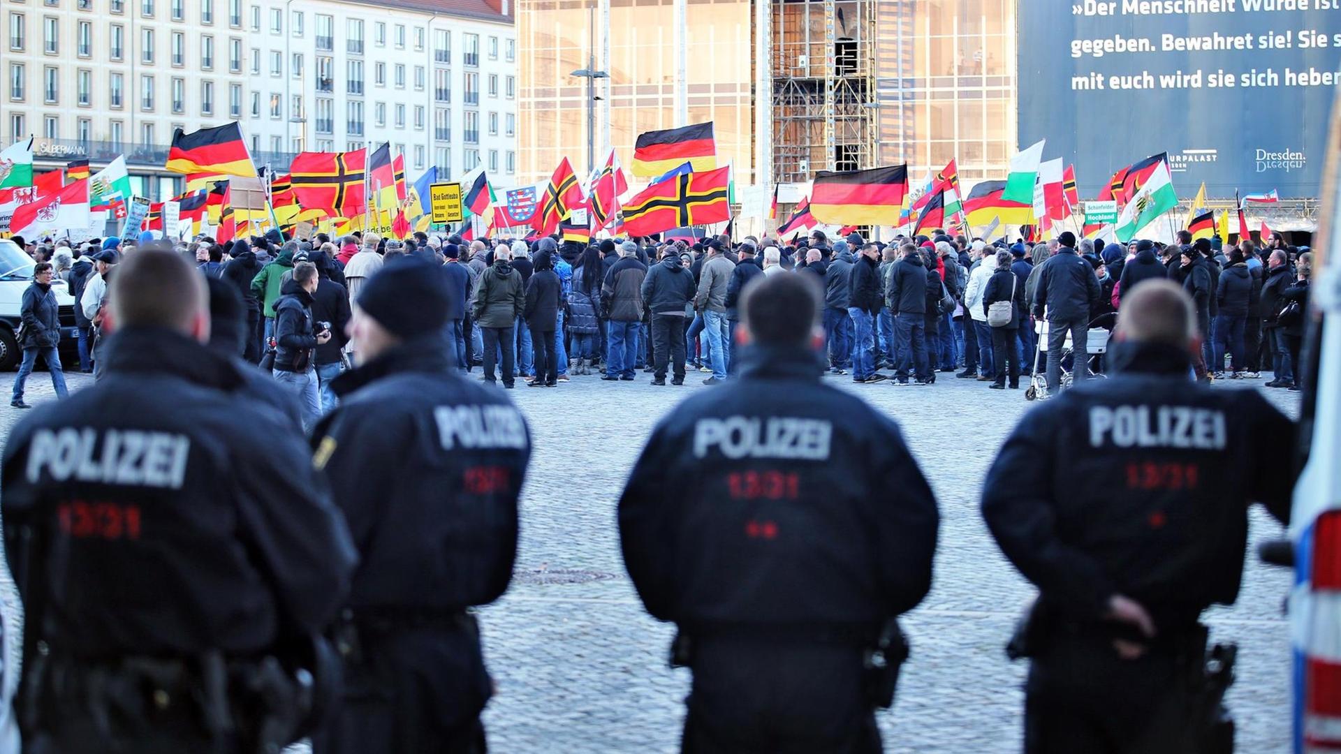 Polizisten vor dem Hintergrund von Anhängern des islamkritischen Pegida-Bündnisses. Polizisten vor dem Hintergrund von Anhängern des islamkritischen Pegida-Bündnisses.