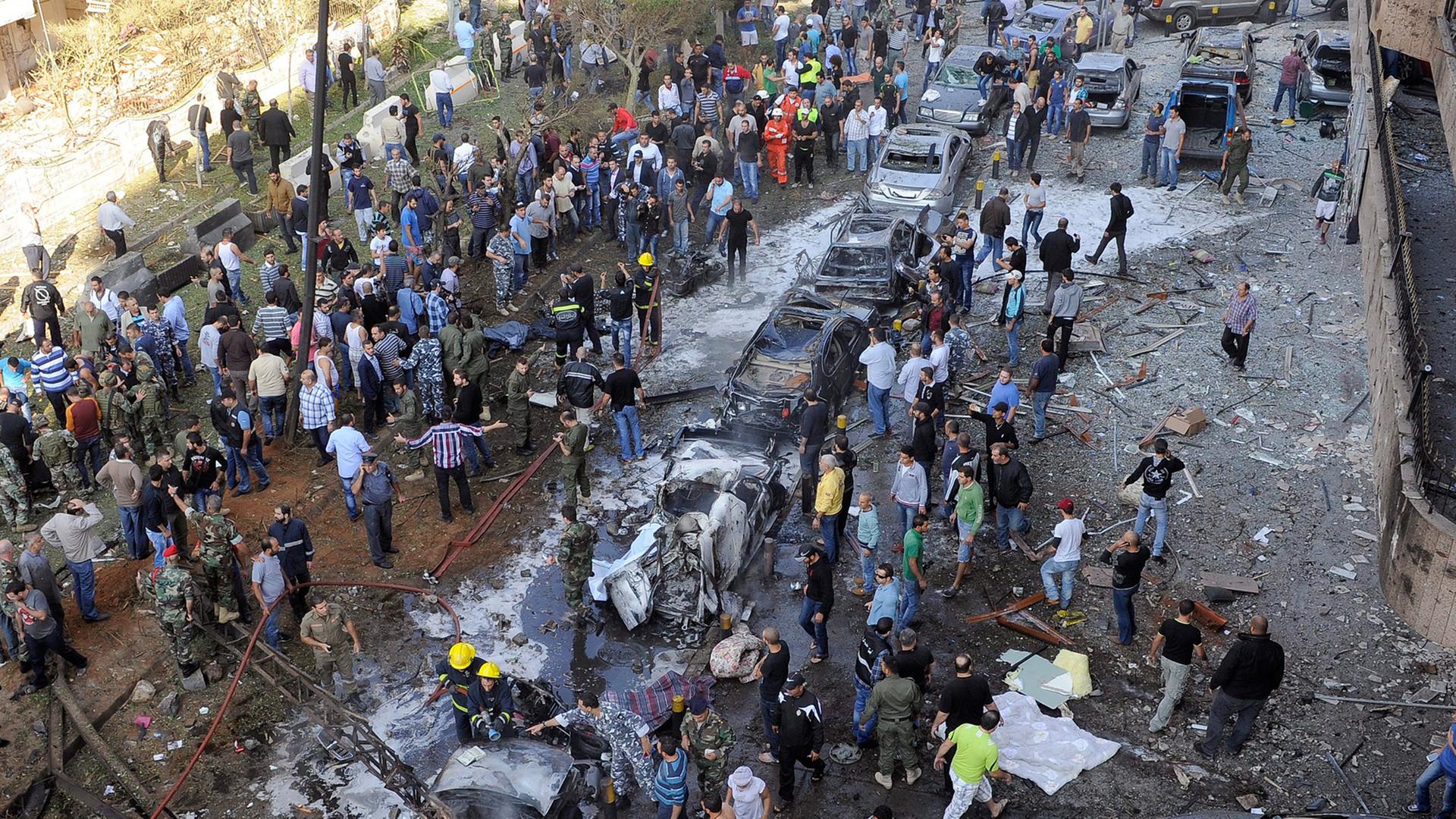 Eine Straße mit ausgebrannten Autos und einer Menschenmenge in der libanesischen Hauptstadt Beirut. Eine Straße mit ausgebrannten Autos und einer Menschenmenge in der libanesischen Hauptstadt Beirut.