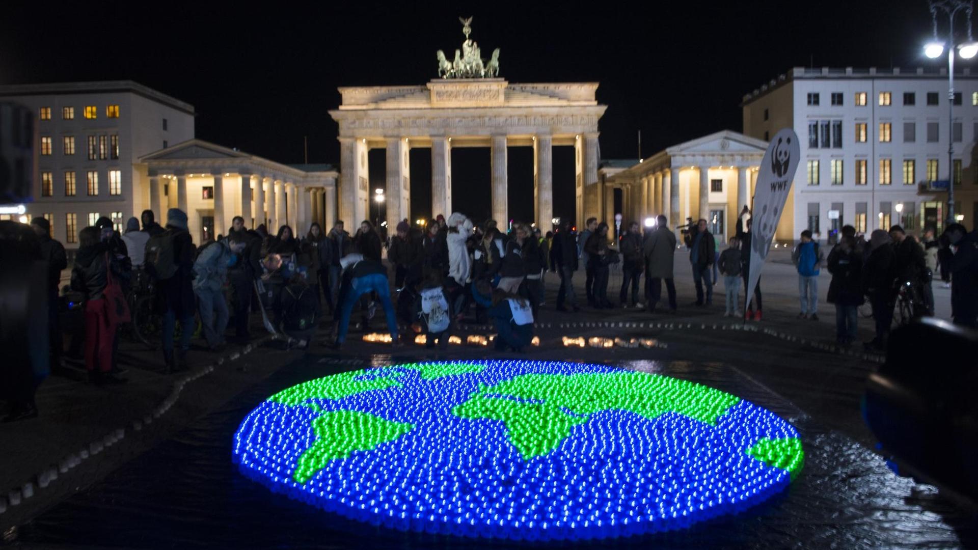 Eine Weltkugel aus LED-Lichtern leuchtet in Berlin vor dem Brandenburger Tor.