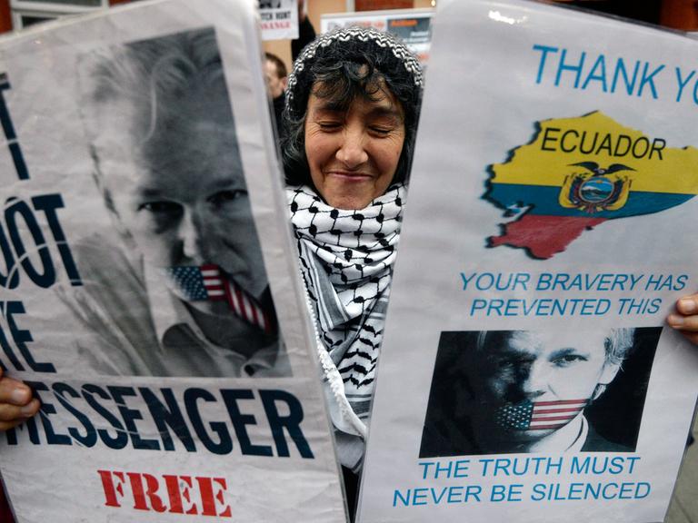 Eine Unterstützerin von Julian Assange hält Plakate hoch vor der ecuadorianischen Botschaft in London.