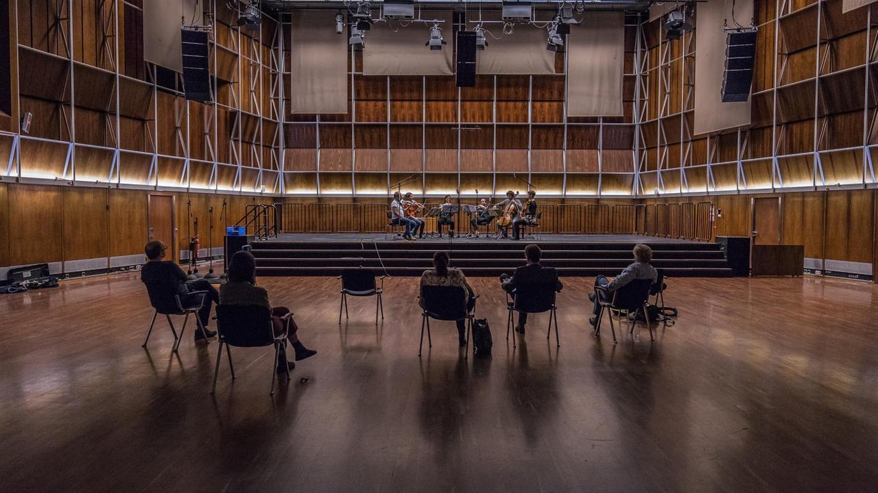Musiker spielen auf der Bühne im holzgetäfelten Dlf Kammermusiksaal, im Raum vereinzelt fünf Zuhörer Musiker spielen auf der Bühne im holzgetäfelten Dlf Kammermusiksaal, im Raum vereinzelt fünf Zuhörer