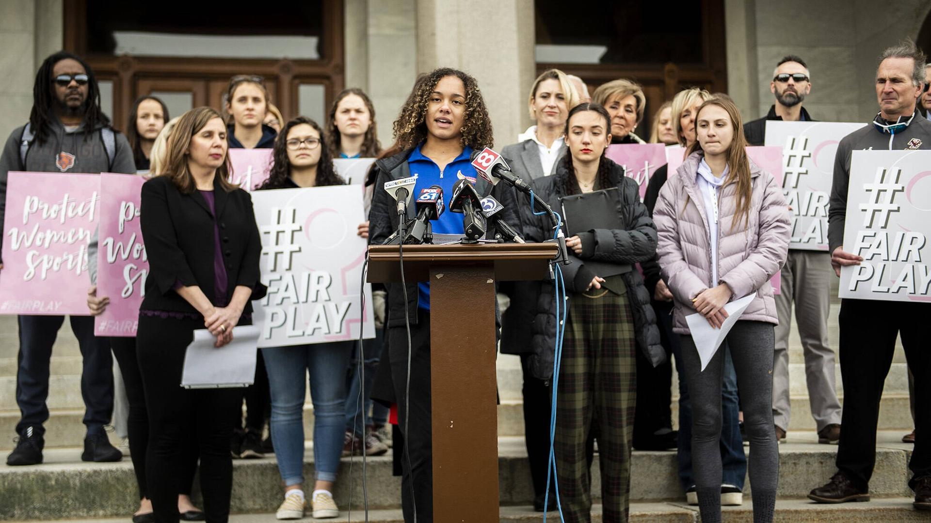 Pressekonferenz in Hartford, Connecticut im Februar 2020. Familien von High-School-Athletinnen hatten gegen die Connecticut Association of Schools geklagt. Sie fühlen sich durch die Teilnahme von Trans-Athletinnen im Frauensport diskriminiert. Sie hätten deshalb weniger Chancen auf Stipendien an Universitäten. In den USA werden zahlreiche Uni-Stipendien an Top-Athlet*innen vergeben. Pressekonferenz in Hartford, Connecticut im Februar 2020. Familien von High-School-Athletinnen hatten gegen die Connecticut Association of Schools geklagt. Sie fühlen sich durch die Teilnahme von Trans-Athletinnen im Frauensport diskriminiert. Sie hätten deshalb weniger Chancen auf Stipendien an Universitäten. In den USA werden zahlreiche Uni-Stipendien an Top-Athlet*innen vergeben.