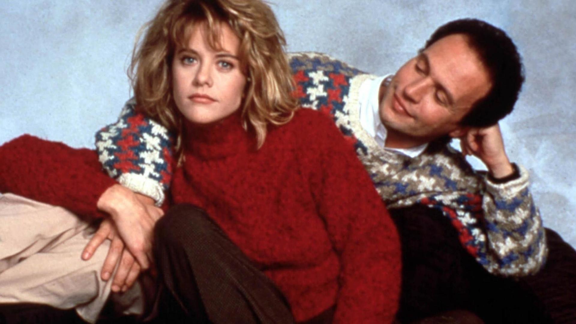 Das Bild zeigt die Schauspieler Meg Ryan und Billy Crystal Händchen haltend. Meg Ryan trägt einen roten Pullover und Billy Crystal einen blauen mit rot-weißem Muster. Das Bild zeigt die Schauspieler Meg Ryan und Billy Crystal Händchen haltend. Meg Ryan trägt einen roten Pullover und Billy Crystal einen blauen mit rot-weißem Muster.