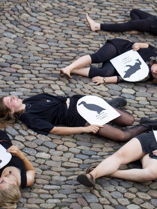 Mehrere junge Menschen liegen auf dem Boden des Augustinerplatzes und haben ein Blatt Papier mit einer aufgedruckten Tierart auf sich liegen.
