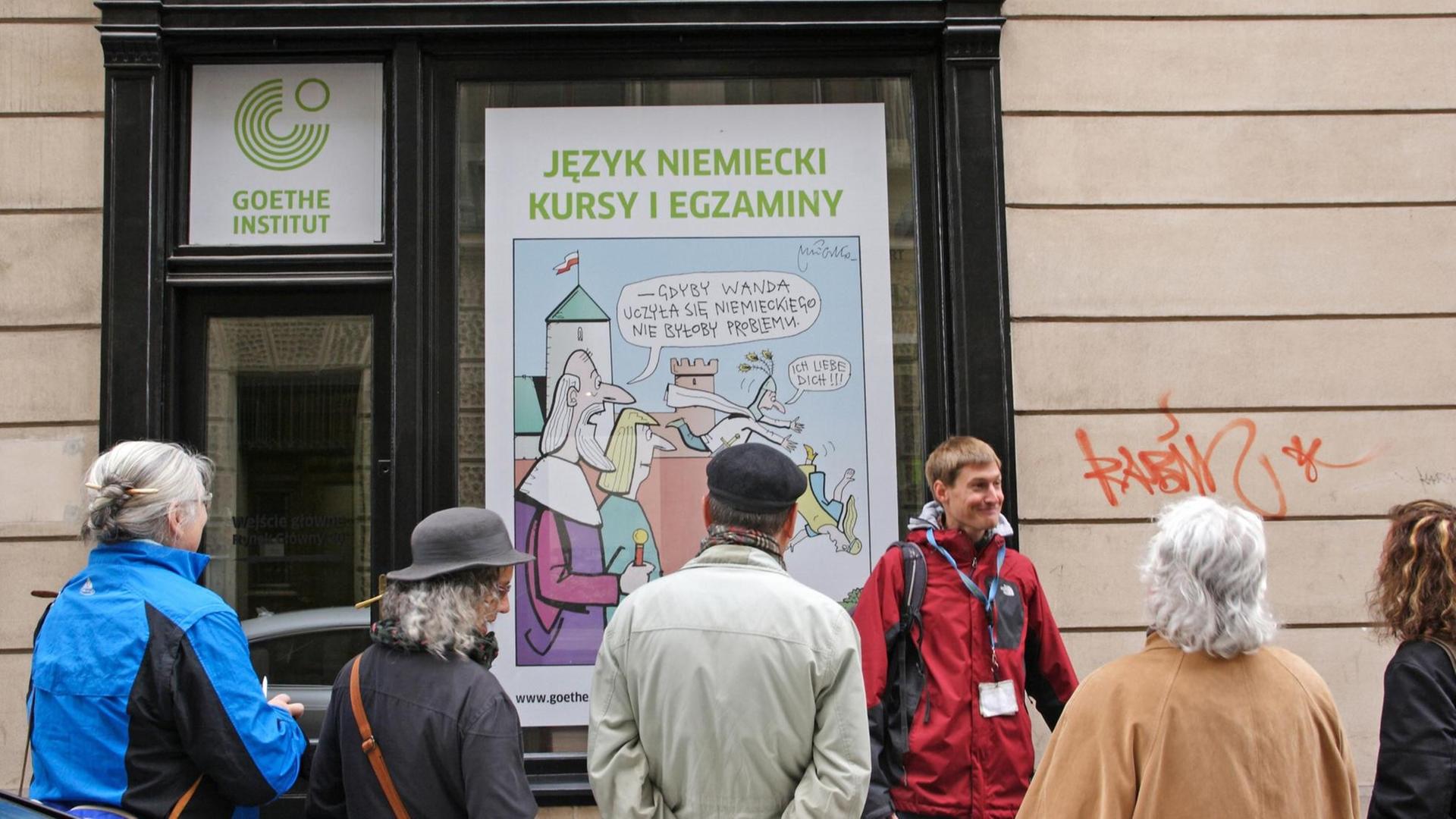 Reisefuehrer mit einer Besuchergruppe vor dem Goethe - Institut in der Altstadt von Krakau in Polen, das fuer Kurse in deutscher Sprache wirbt, aufgenommen am 28.5.2015. Foto: Rainer Oettel | Verwendung weltweit Reisefuehrer mit einer Besuchergruppe vor dem Goethe - Institut in der Altstadt von Krakau in Polen, das fuer Kurse in deutscher Sprache wirbt, aufgenommen am 28.5.2015. Foto: Rainer Oettel | Verwendung weltweit