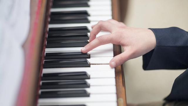 Nahaufnahme von einer Hand, die Klavier spielt.