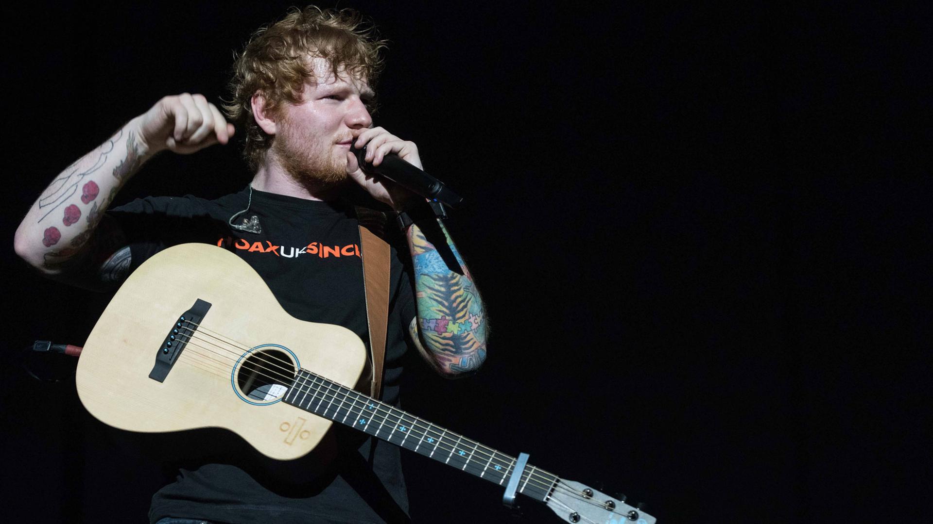 Sänger Ed Sheeran mit einer Gitarre und Mikrofon in der Hand während eines Konzertes