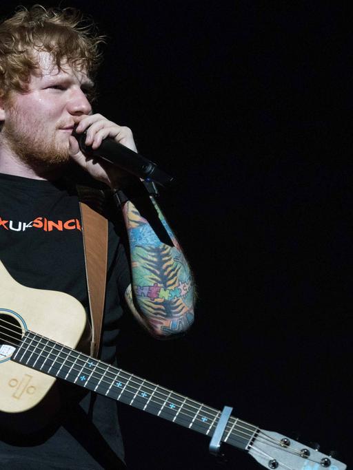 Sänger Ed Sheeran mit einer Gitarre und Mikrofon in der Hand während eines Konzertes