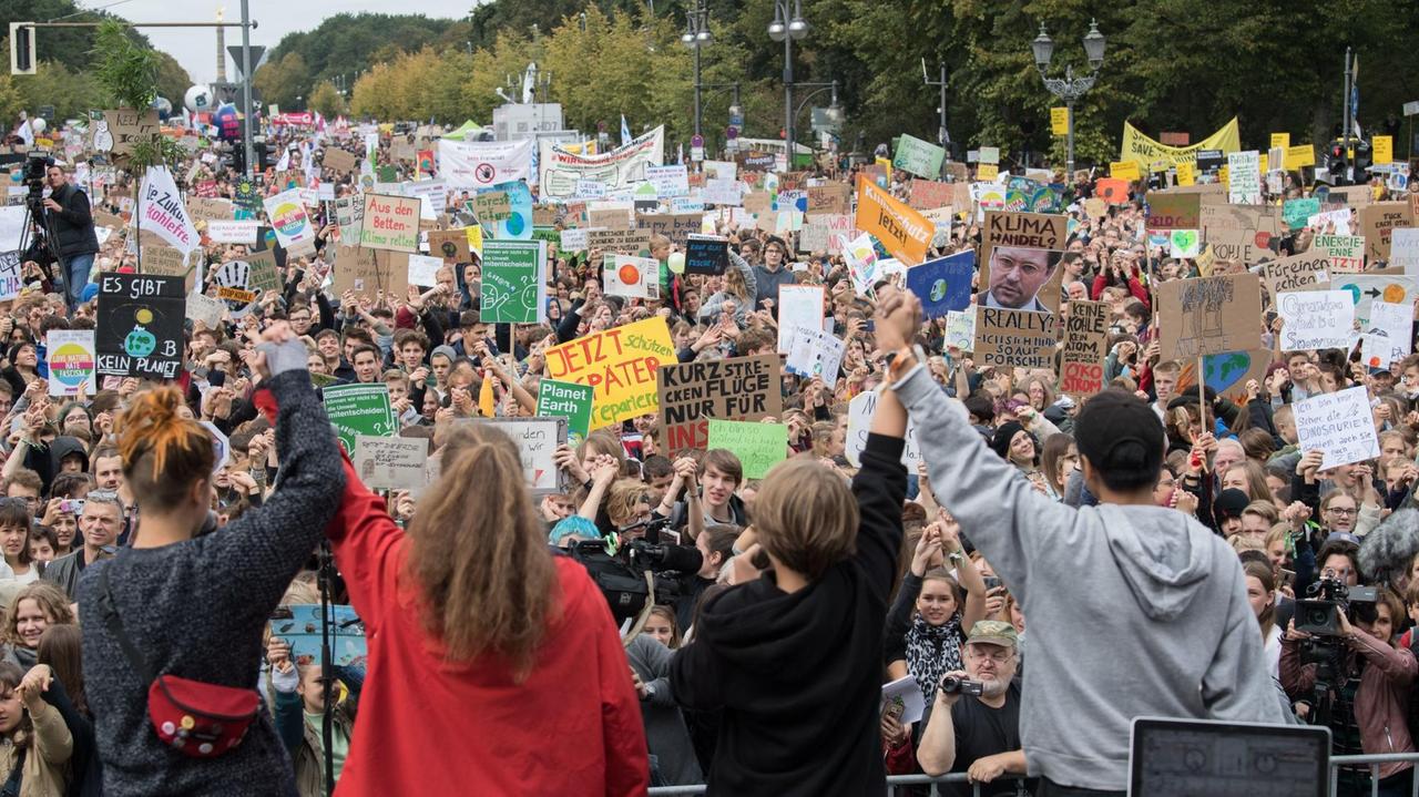 Demonstranten nehmen am Klima-Protesttag von Fridays For Future vor dem Brandenburger Tor teil und stehen vor der Bühne. 