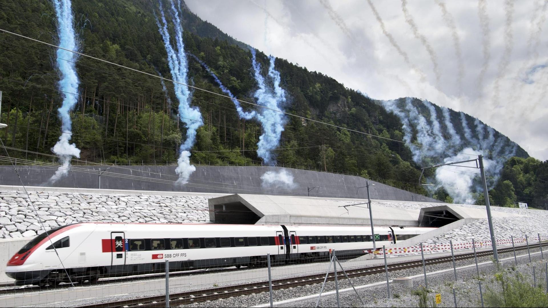 Ein Zug fährt in den Tunnel ein, dahinter Rauchsäulen von Feuerwerkskörpern.