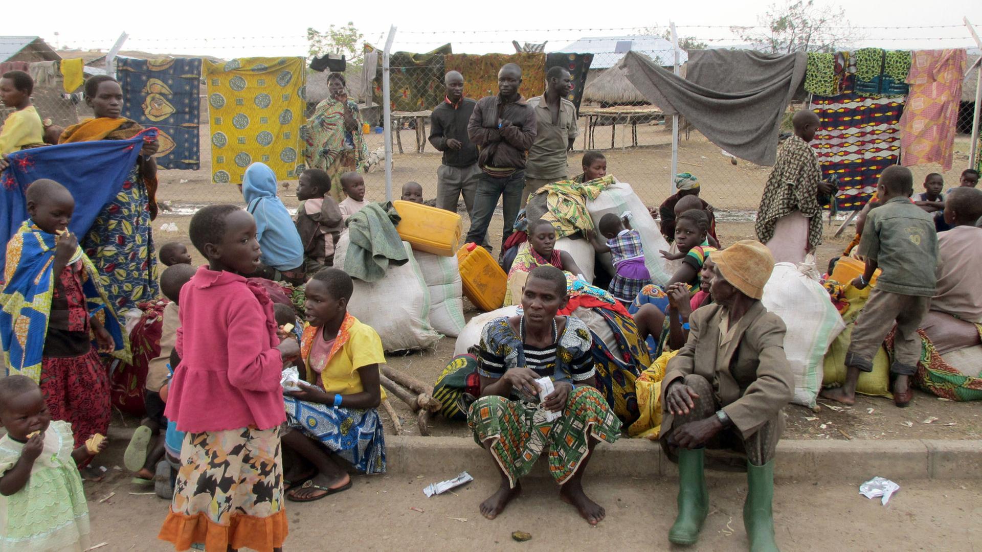Aus dem Kongo kommende Flüchtlinge sitzen am 06.03.2018 im ugandischen Sebagoro auf dem Boden.