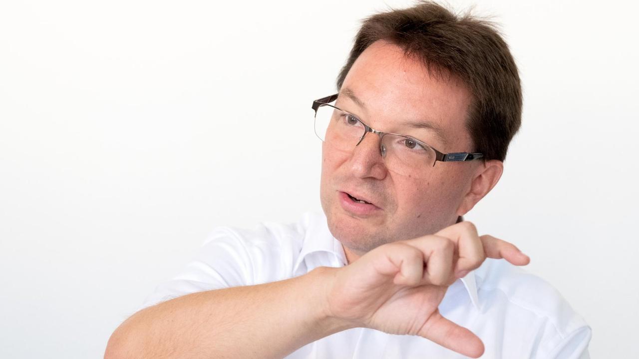 Michael Blum, der Antisemitismusbeauftragte des Landes Baden-Württemberg, sitzt in einem weißen Hemd vor weißem Hintergrund und gestikuliert mit der rechten Hand. Michael Blum, der Antisemitismusbeauftragte des Landes Baden-Württemberg, sitzt in einem weißen Hemd vor weißem Hintergrund und gestikuliert mit der rechten Hand.