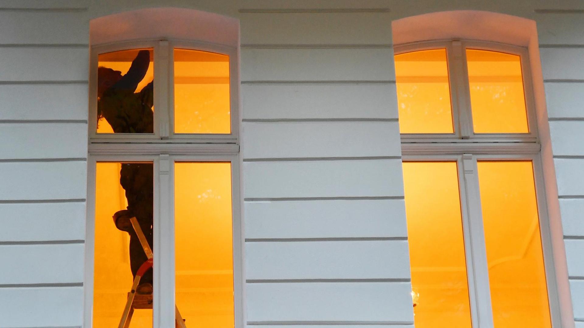 Ein Mann steht in Berlin an einem Fenster in einer Wohnung auf einer Leiter. Ein Mann steht in Berlin an einem Fenster in einer Wohnung auf einer Leiter.