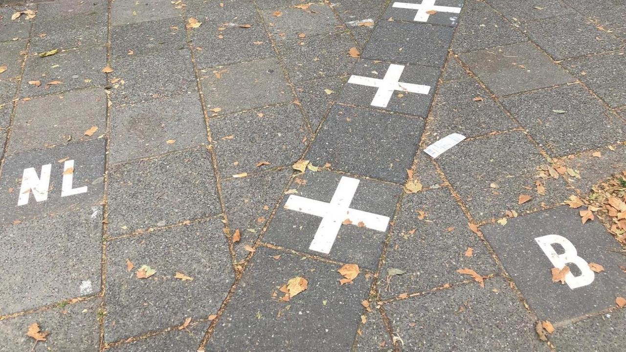 Weiße Kreuze auf dem Bürgersteig markieren die Grenze zwischen Belgien und den Niederlanden. Weiße Kreuze auf dem Bürgersteig markieren die Grenze zwischen Belgien und den Niederlanden.