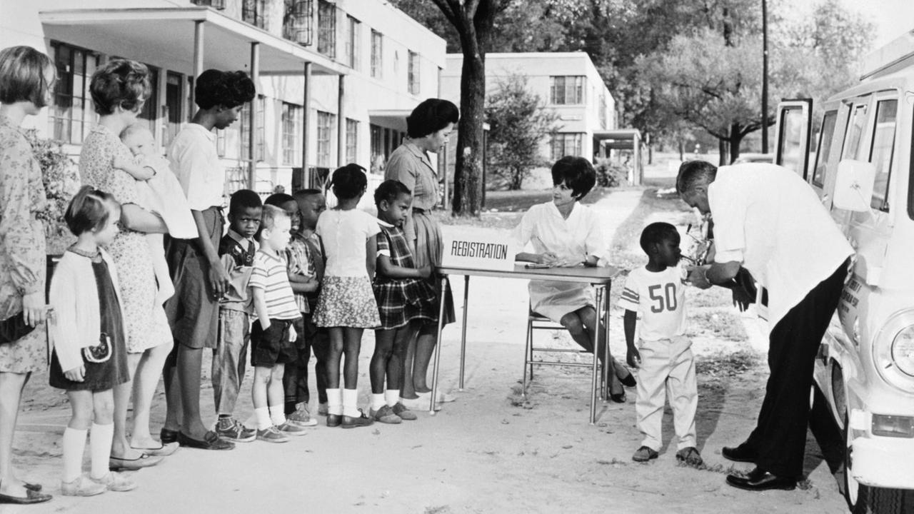 USA 1972: Ein kleiner schwarzer Junge bekommt eine Impf-Injektion. In einer Reihe daneben warten schwarze und weiße Kinder, begleitet von ihren Müttern. Die Szene wurde in der fiktiven "Dixon Tiller County" verortet, einer Modellgemeinde der US-Gesundheitsbehörden - und wurde als Lehrmaterial für Impfaufklärung verwendet USA 1972: Ein kleiner schwarzer Junge bekommt eine Impf-Injektion. In einer Reihe daneben warten schwarze und weiße Kinder, begleitet von ihren Müttern. Die Szene wurde in der fiktiven "Dixon Tiller County" verortet, einer Modellgemeinde der US-Gesundheitsbehörden - und wurde als Lehrmaterial für Impfaufklärung verwendet