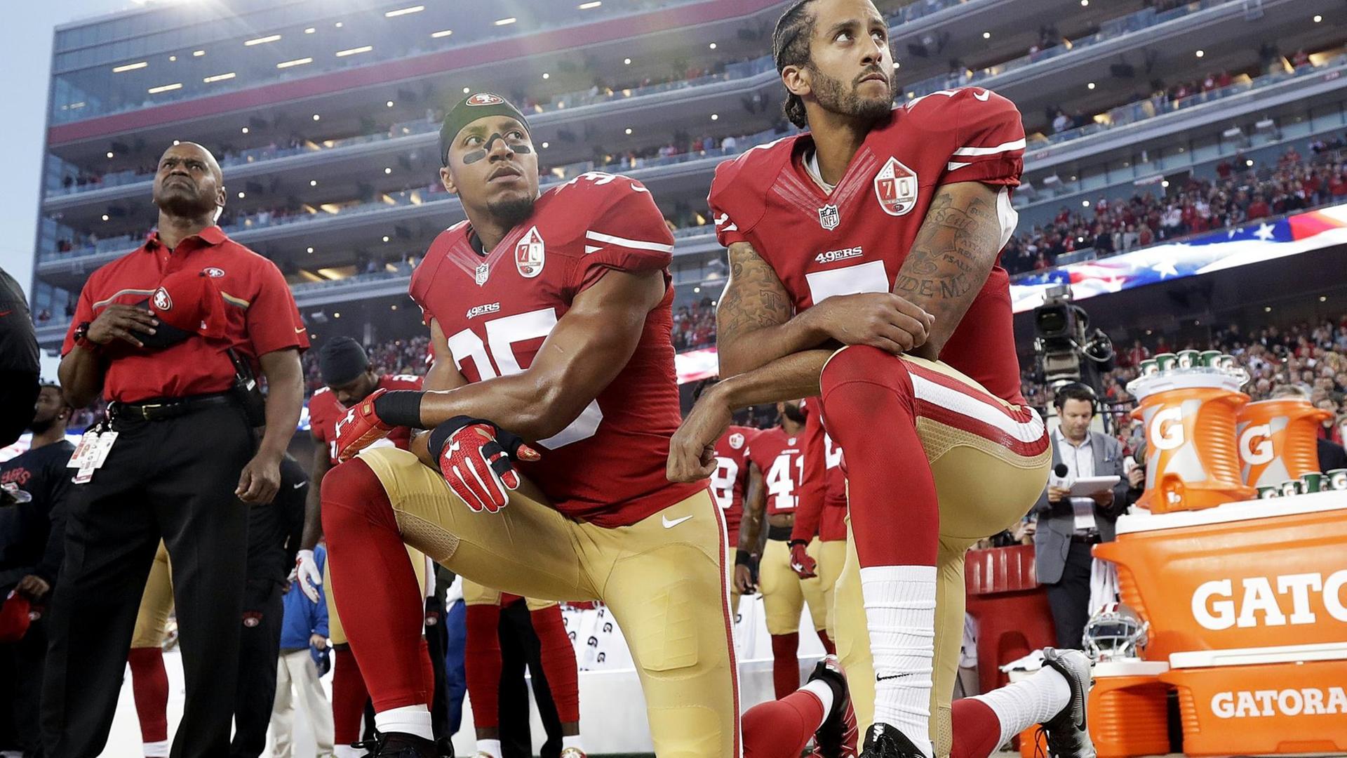 Drei Spieler der NFL-Mannschaft "San Francisco 49ers" knien während der Nationalhymne vor einem Football-Spiel Drei Spieler der NFL-Mannschaft "San Francisco 49ers" knien während der Nationalhymne vor einem Football-Spiel