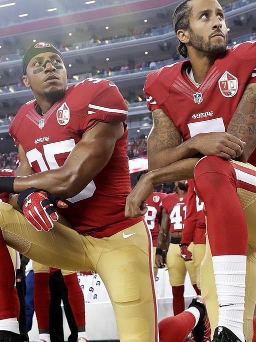 Drei Spieler der NFL-Mannschaft "San Francisco 49ers" knien während der Nationalhymne vor einem Football-Spiel
