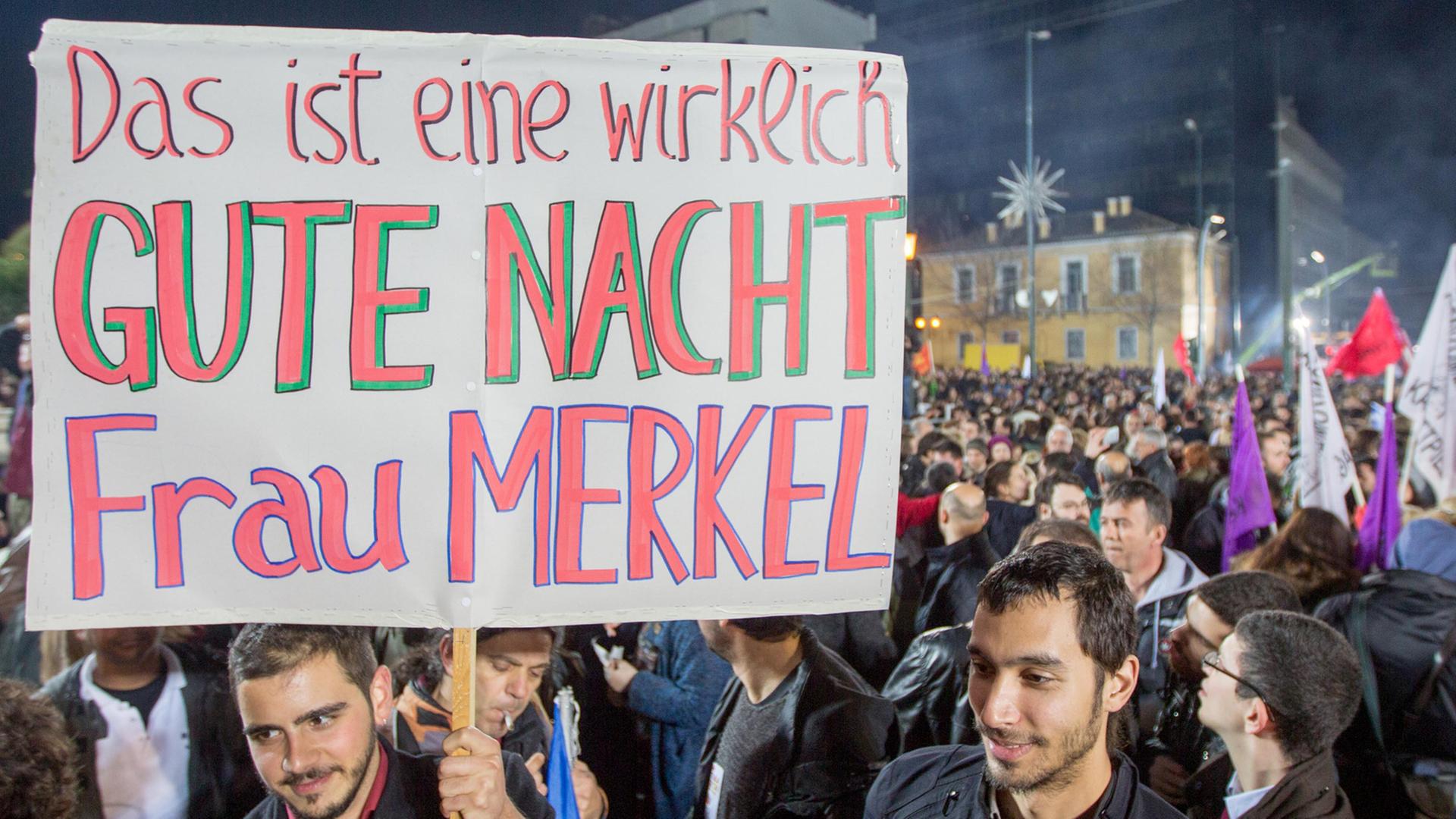 Syriza-Anhänger halten ein Schild hoch mit der Aufschrift "Das ist eine wirklich GUTE NACHT Frau Merkel". Syriza-Anhänger halten ein Schild hoch mit der Aufschrift "Das ist eine wirklich GUTE NACHT Frau Merkel".