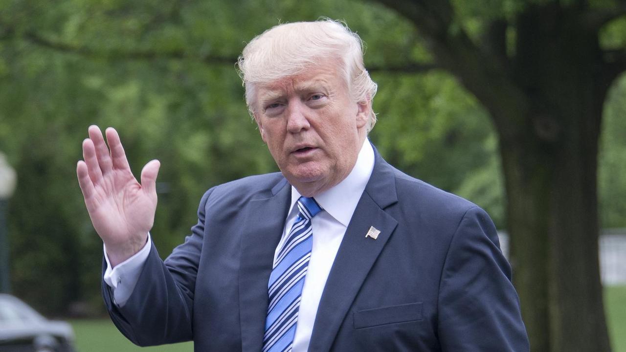 Trump winkt vor grünen Büschen und Bäumen mit der Hand. Trump winkt vor grünen Büschen und Bäumen mit der Hand.