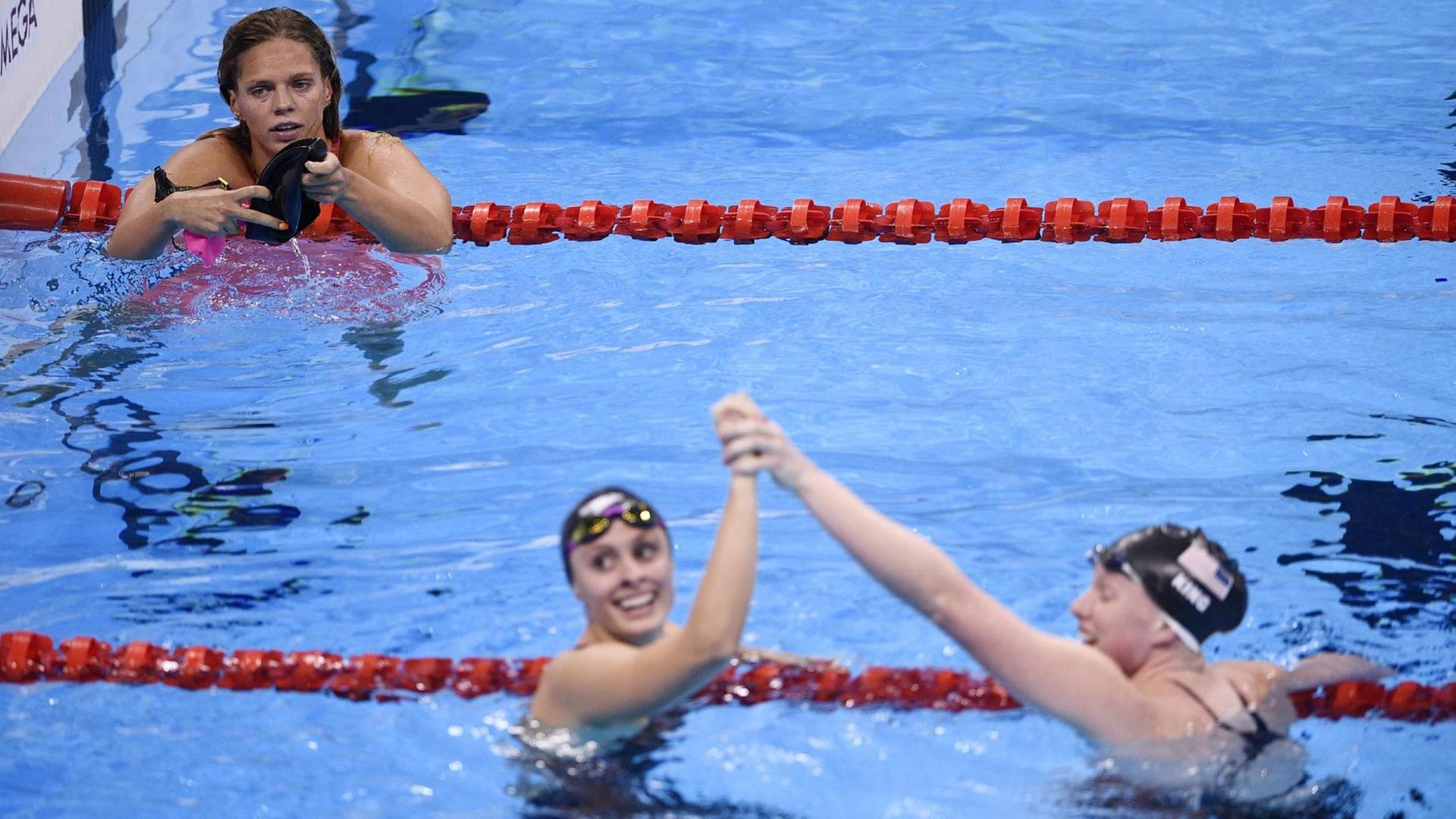 Die Schwimmerinnnen Lilly King und Karie Meili klatschen sich im Becken ab, Julia Jefimowa bleibt außen vor.