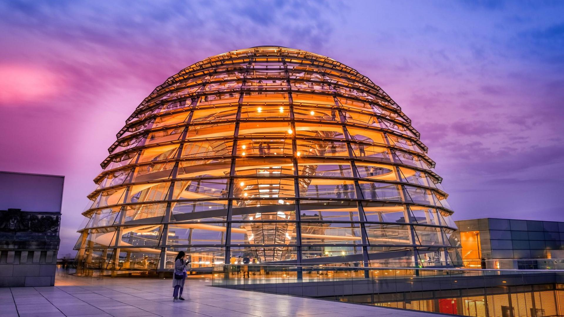 Die orange illuminierte Reichstagskuppel bei Abenddämmerung. Die orange illuminierte Reichstagskuppel bei Abenddämmerung.