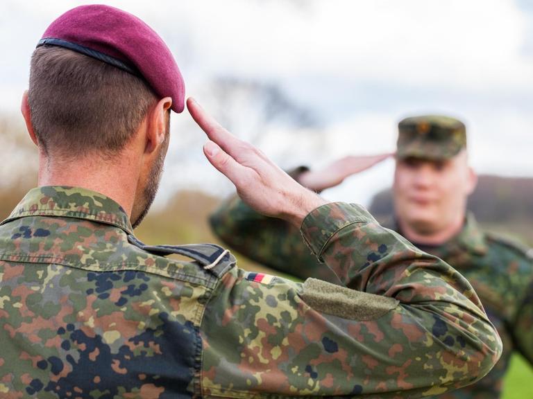 Zwei deutsche Soldaten der Bundeswehr salutieren einander.