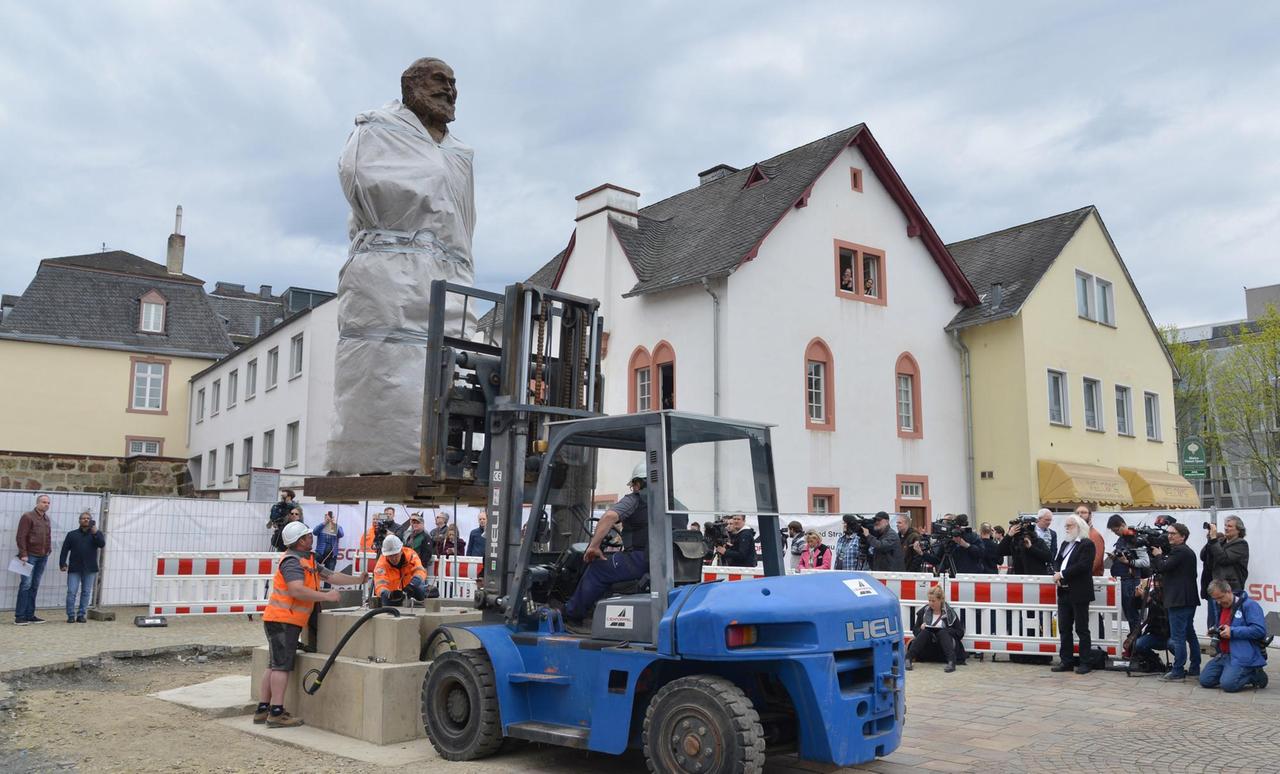 Die größtenteils mit einer Plane verdeckte 2,3 Tonnen schwere und 4,40 Meter große Karl-Marx-Statue des chinesischen Künstlers Wu Weishan wird in Trier aufgestellt. Die größtenteils mit einer Plane verdeckte 2,3 Tonnen schwere und 4,40 Meter große Karl-Marx-Statue des chinesischen Künstlers Wu Weishan wird in Trier aufgestellt.