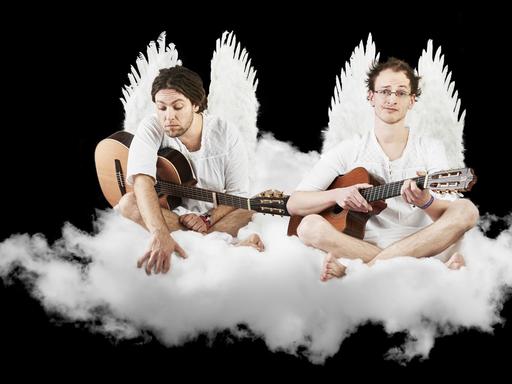 Das Duo als Engel verkleidet auf einer bauschigen, weißen Wolke sitzend