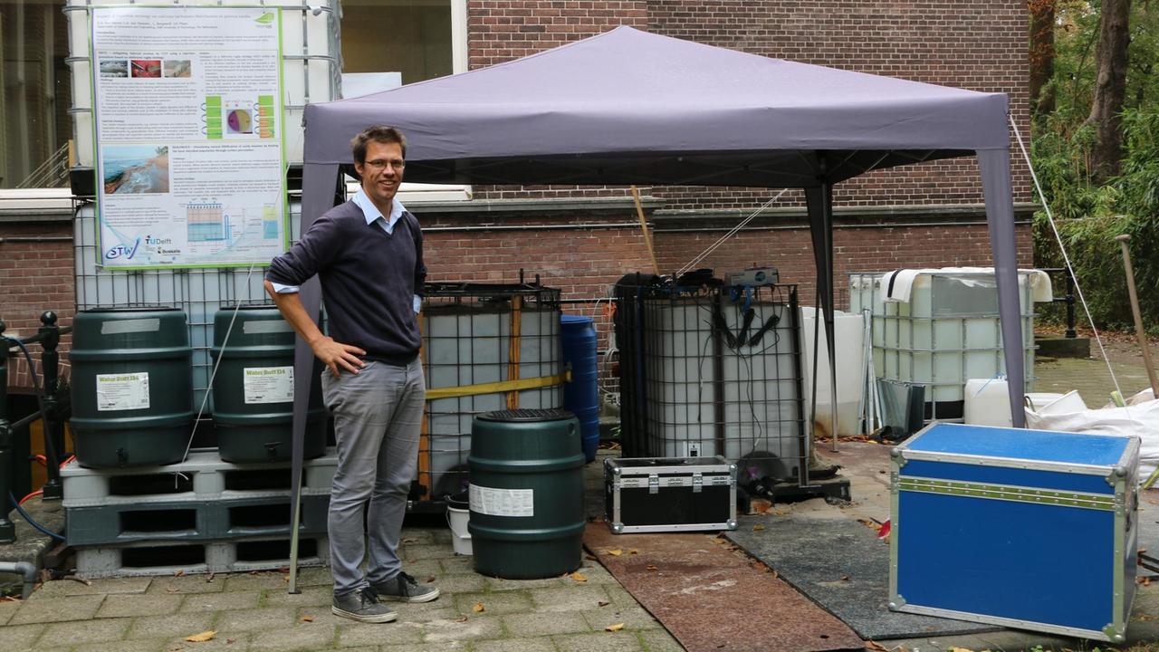 Leon van Paassen von der TU Delft, Niederlande. Im Hintergrund die beiden jeweils einen Kubikmeter großen Boxen, in denen Bakterien Strandsand verfestigen sollen Leon van Paassen von der TU Delft, Niederlande. Im Hintergrund die beiden jeweils einen Kubikmeter großen Boxen, in denen Bakterien Strandsand verfestigen sollen