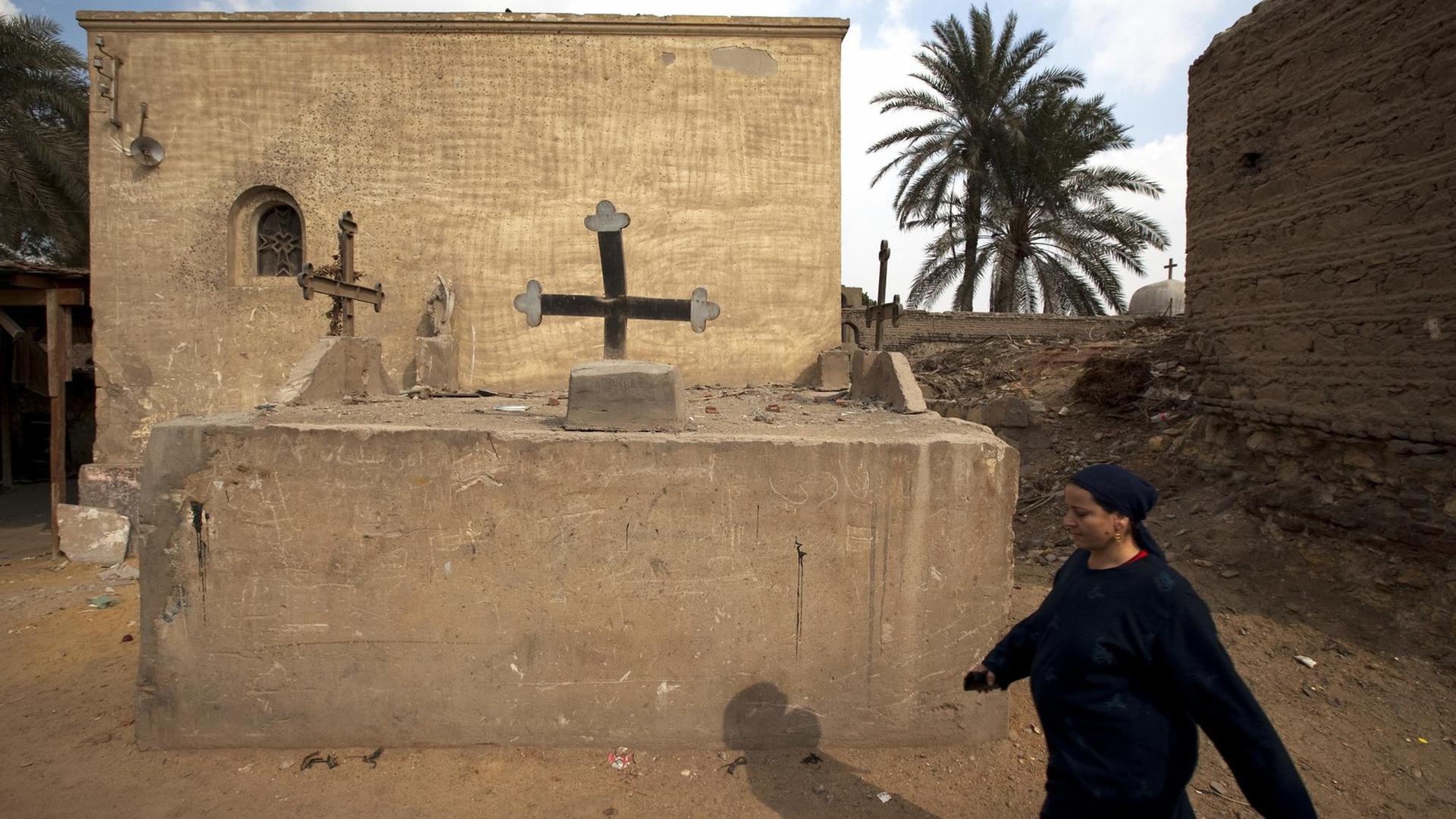 Eine koptische Frau läuft auf dem Friedhof des Koptenviertels in Kairo an einer Grabstätte vorbei (Aufnahme vom 21.1.2010). Eine koptische Frau läuft auf dem Friedhof des Koptenviertels in Kairo an einer Grabstätte vorbei (Aufnahme vom 21.1.2010).