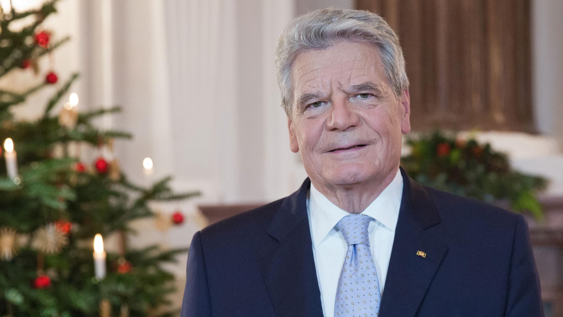 Bundespräsident Gauck steht während seiner Weihnachtsansprache 2013 im Schloss Bellevue vor einem geschmückten Weihnachtsbaum.