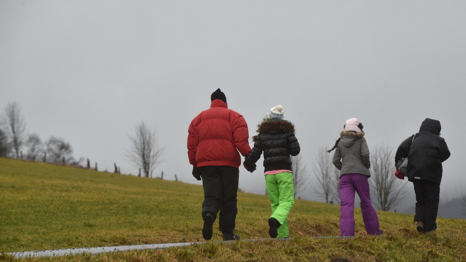 Eine Urlauberfamilie geht am bei stürmischen Regenwetter im hessischen Willingen spazieren.