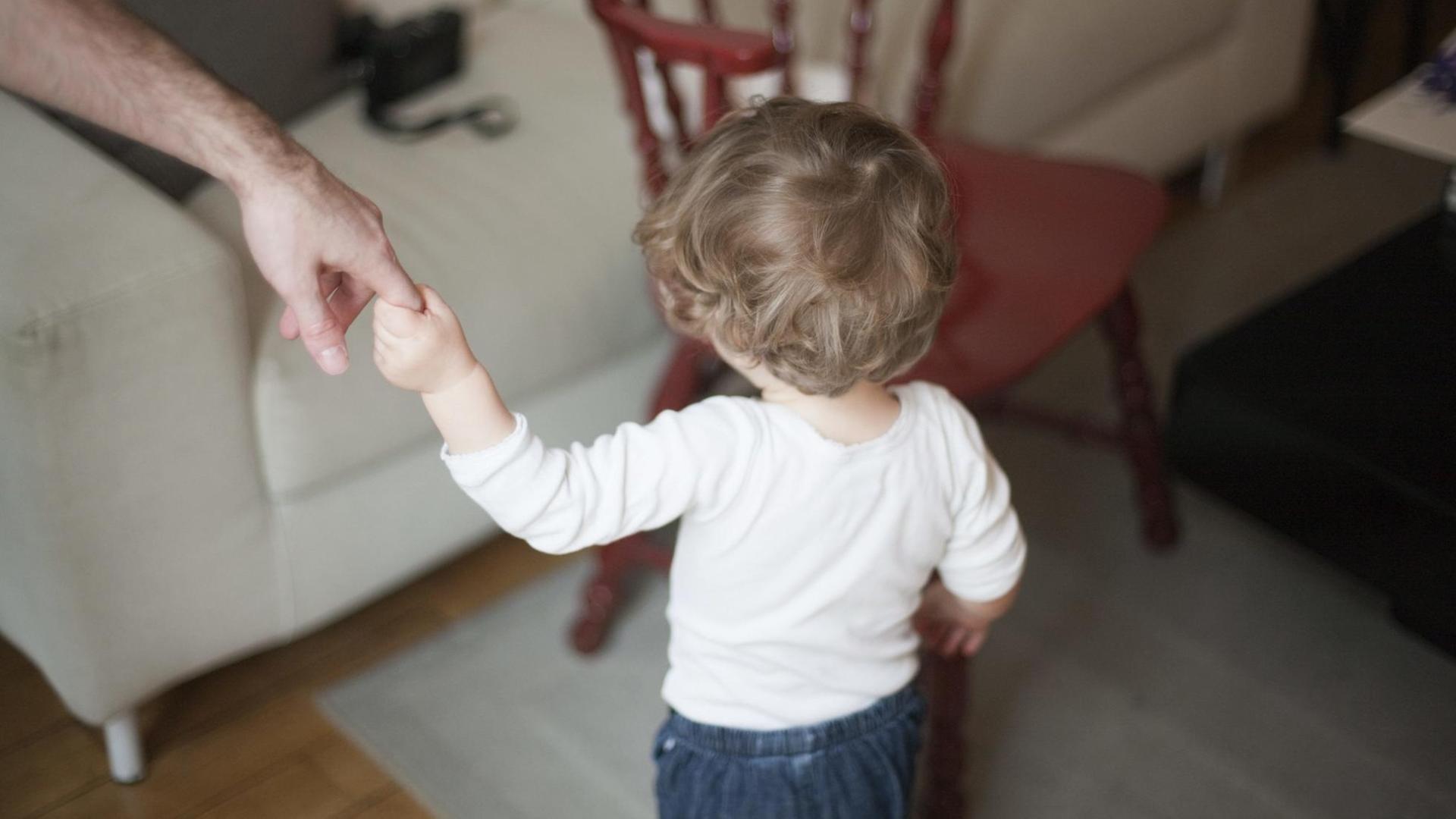 Mann hält ein Kind an der Hand Mann hält ein Kind an der Hand