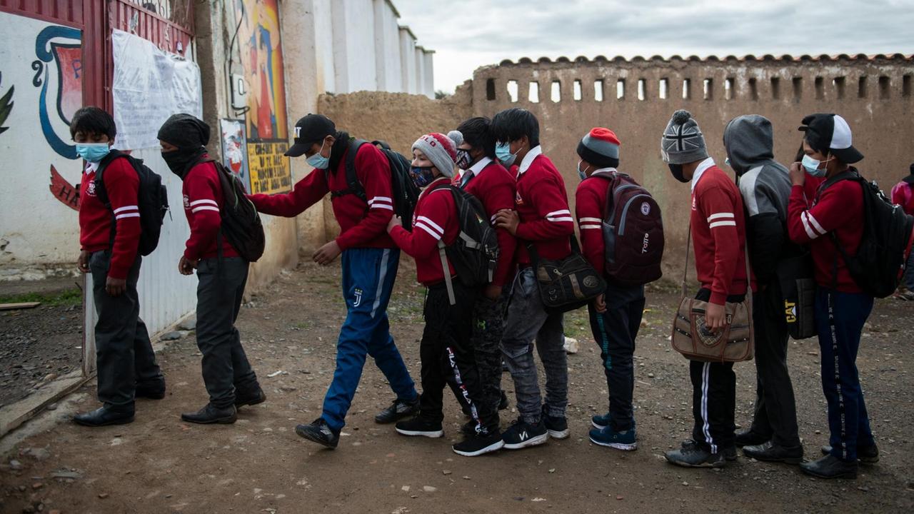 Schüler mit Masken stehen Schlange vor dem Eingang von einer Schule in Bolivien. Schüler mit Masken stehen Schlange vor dem Eingang von einer Schule in Bolivien.